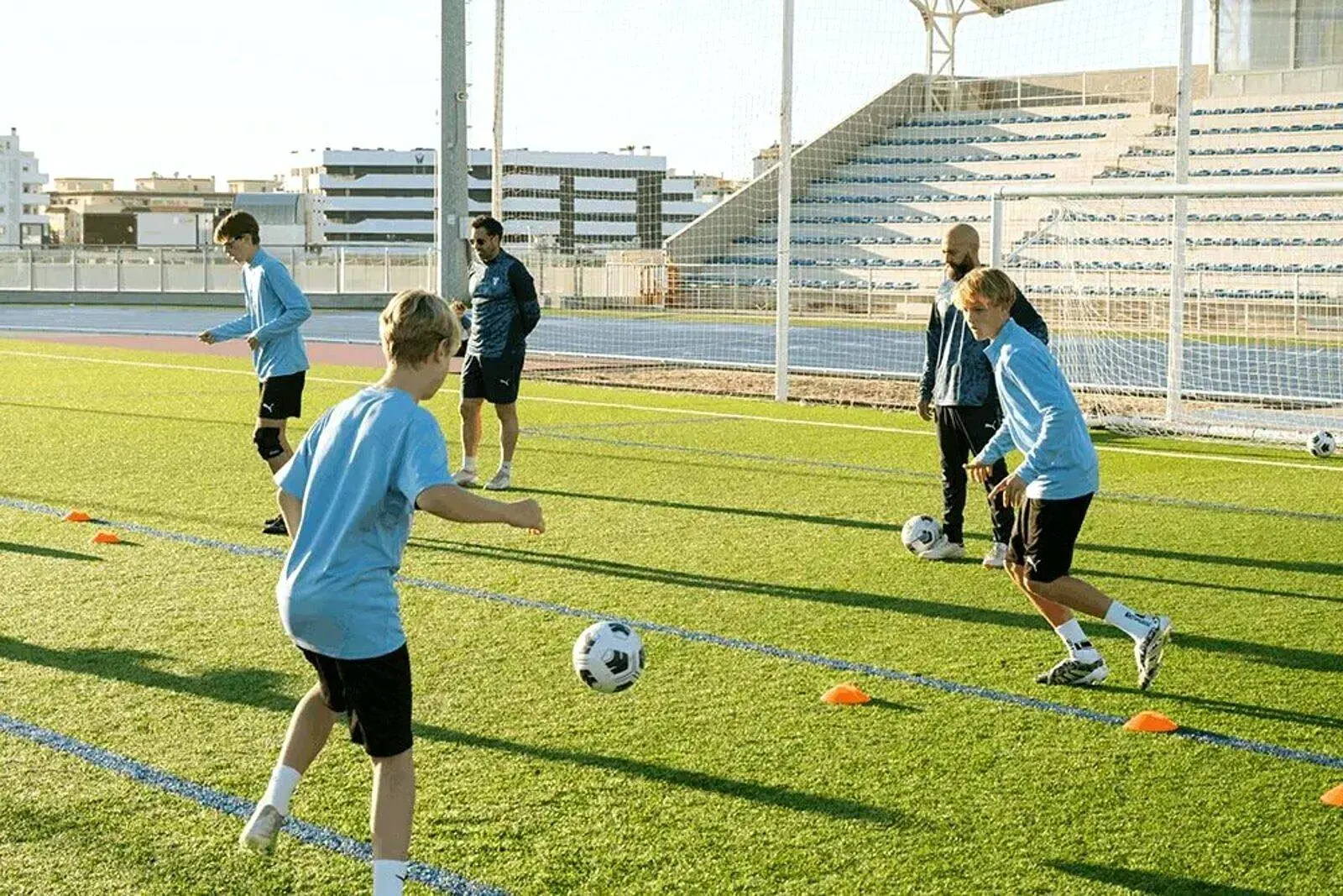 Jóvenes entrenando pases en el campo de hierba durante el campus de fútbol