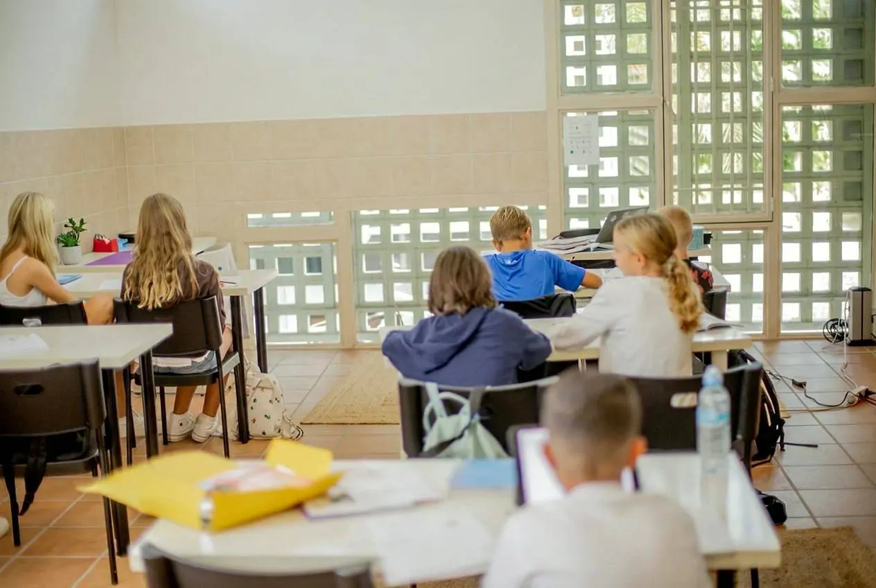 Elever som arbetar med böcker och iPads i ett ljust klassrum